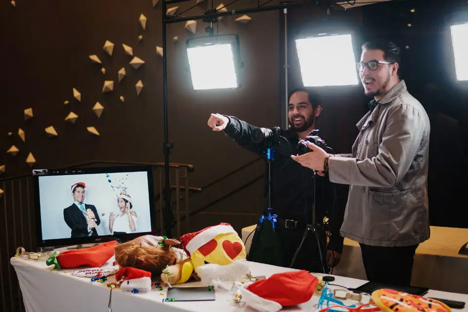 Photographers setting up a photo booth with props and lighting at a vendor booth.