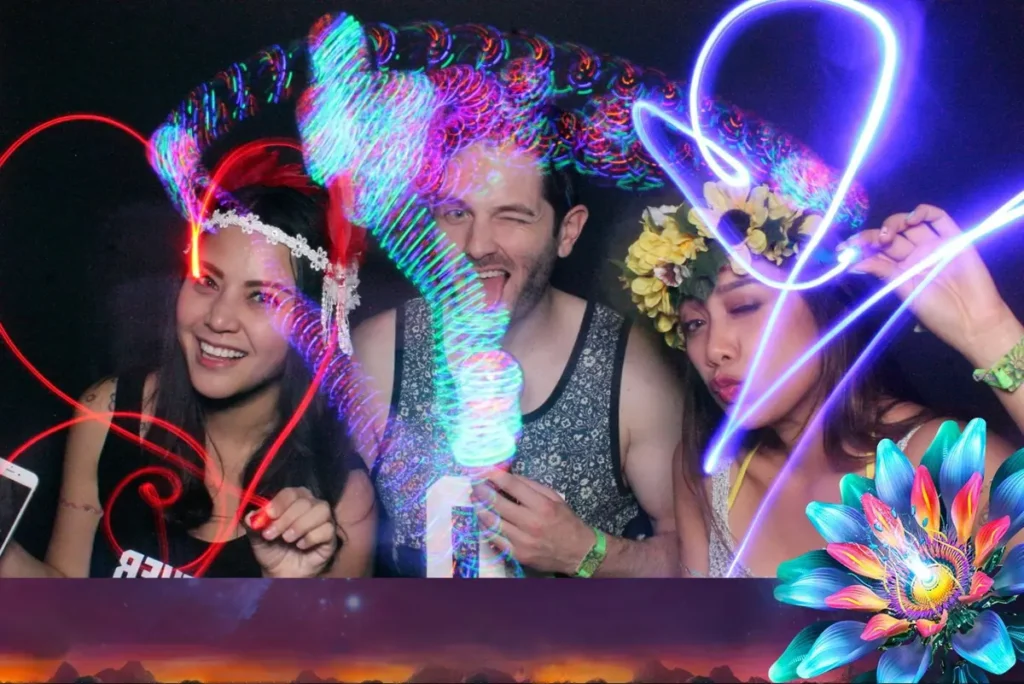 Three friends enjoying a vibrant AI photo booth experience with neon light trails and artistic effects, creating a dynamic and immersive party atmosphere