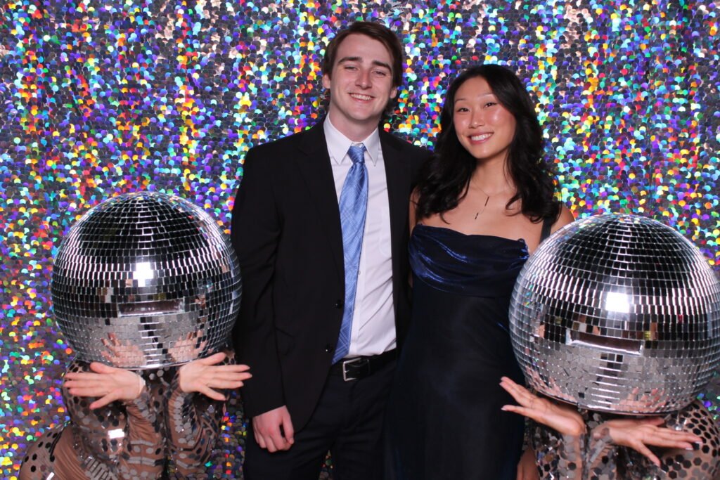 A well-dressed couple posing against a dazzling, colorful sequined backdrop.