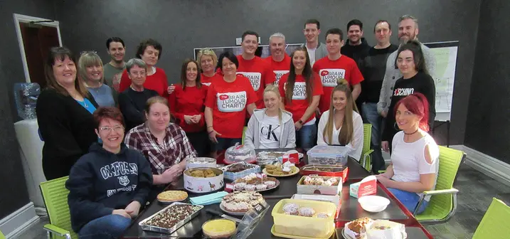Office team gathered for a charity bake sale with tables filled with desserts.