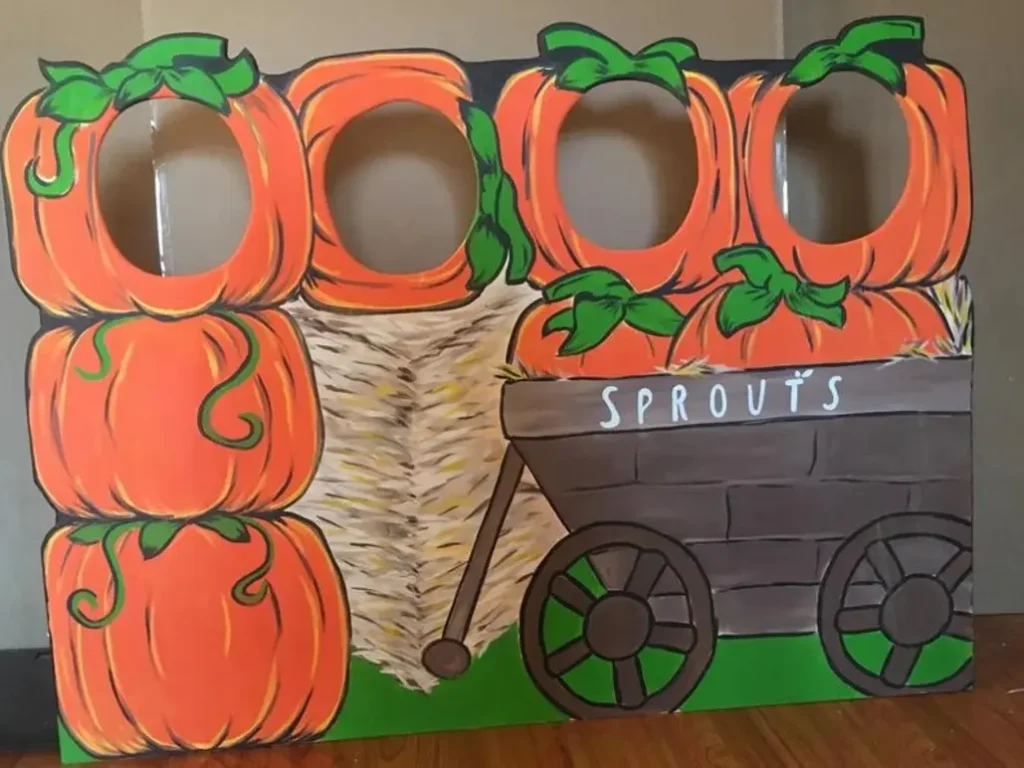 Pumpkin-themed cutout photo booth backdrop with face holes for posing.