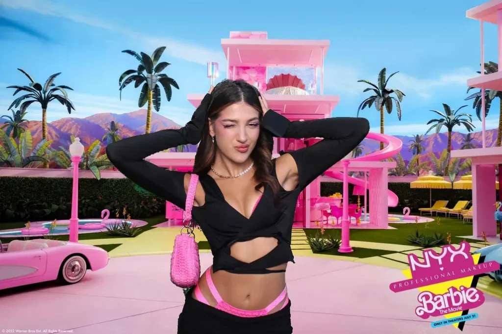 Young woman posing with a Barbie-themed photo booth backdrop at a festival.