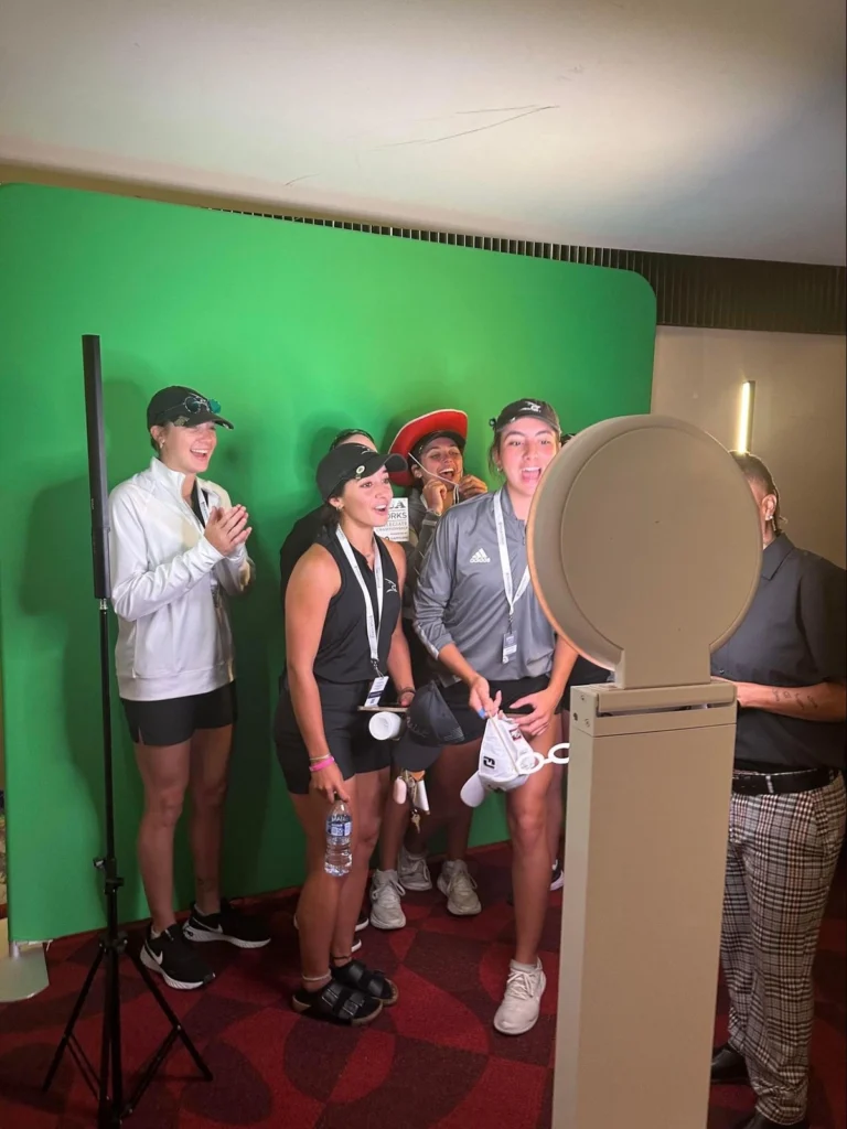 Group of athletes smiling and laughing while recording video testimonials against a green screen backdrop