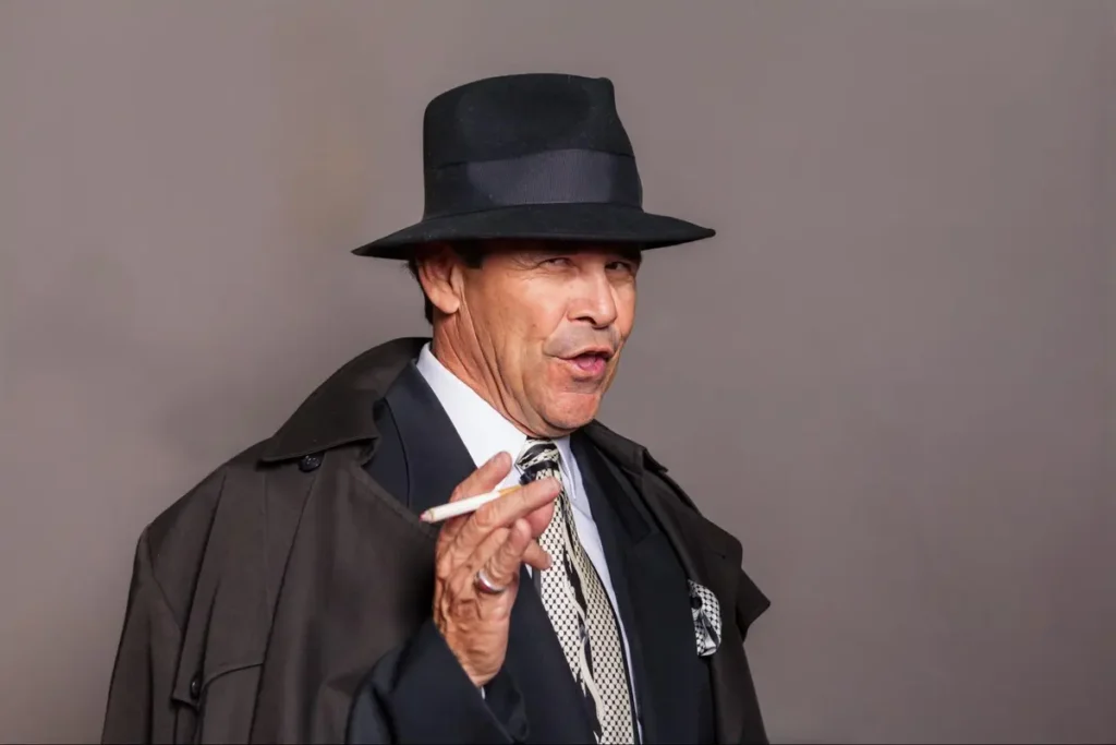 Portrait photography of man in vintage noir style with fedora and trench coat, showcasing retro fashion photography