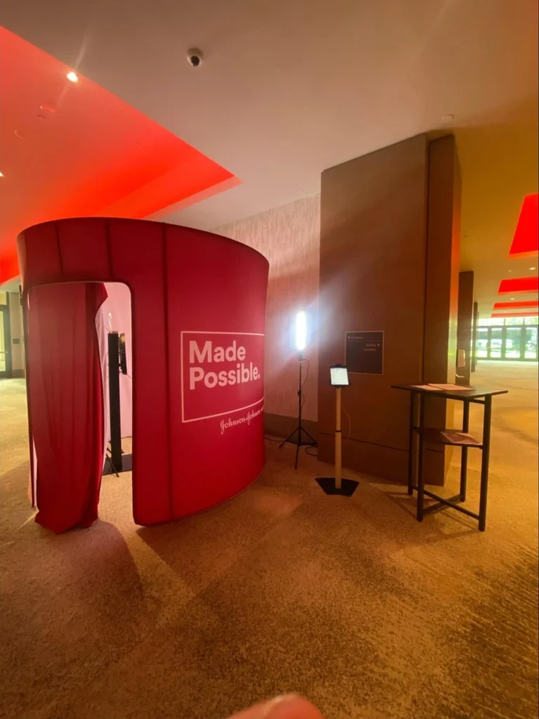 Red circular video confessional booth with Made Possible branding by Johnson & Johnson, with lighting setup for testimonials