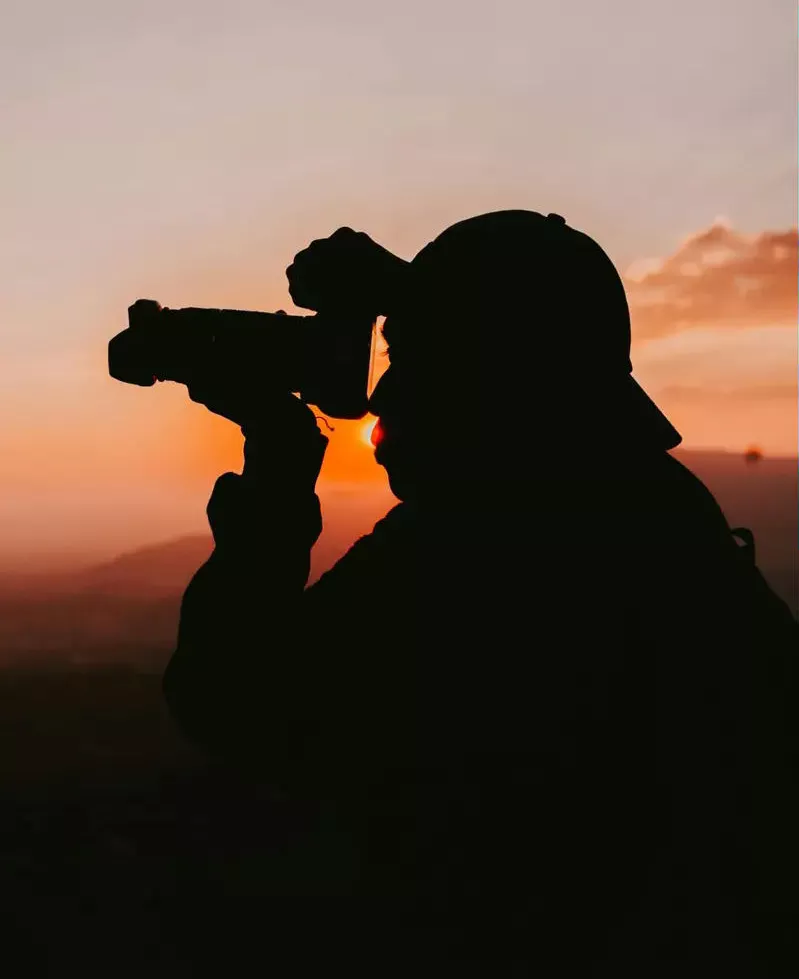 Silhouette of photographer against vibrant sunset, capturing golden hour photography trends with dramatic lighting