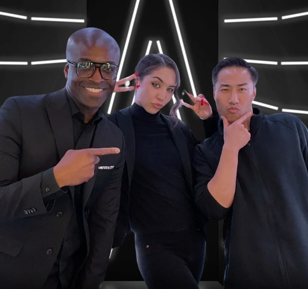 Three diverse professionals in black attire posing playfully against modern geometric lighting backdrop