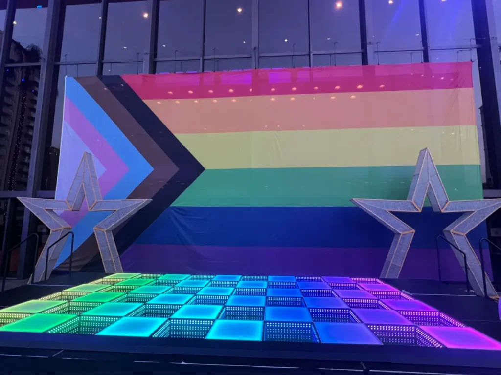 Colorful LED dance floor with rainbow backdrop and star decorations - perfect for themed events requiring advance booking