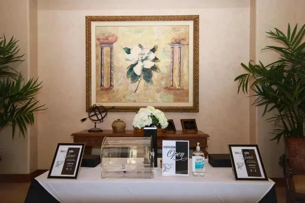 Elegant corporate event registration table with alphabetical check-in signs, hand sanitizer station, and professional decor for organized arrivals