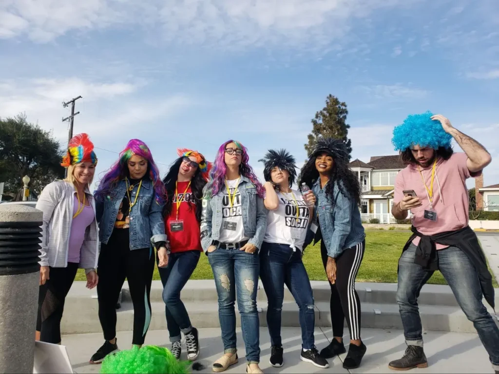 Group of colleagues wearing colorful wigs at a team building event, showing fun corporate entertainment that boosts engagement
