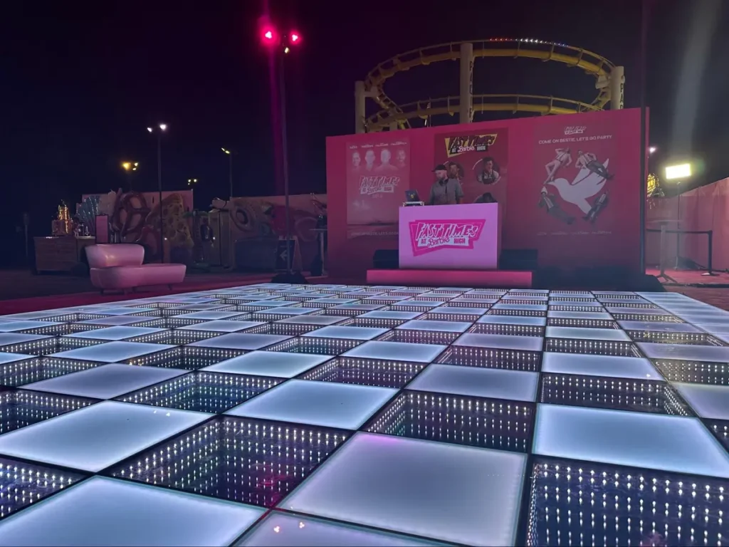 Illuminated LED dance floor at themed outdoor event with DJ booth and stage - specialty installations need advance planning