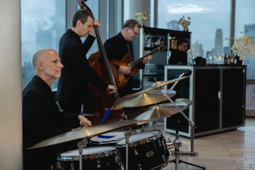 Jazz trio performing live music at corporate event with upscale bar setup and city skyline views, creating sophisticated ambiance