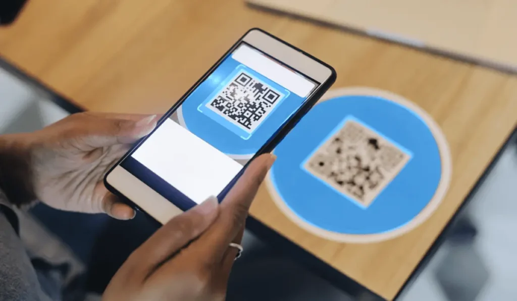 Person scanning a QR code displayed on a circular blue marker using their smartphone, demonstrating easy digital engagement at events