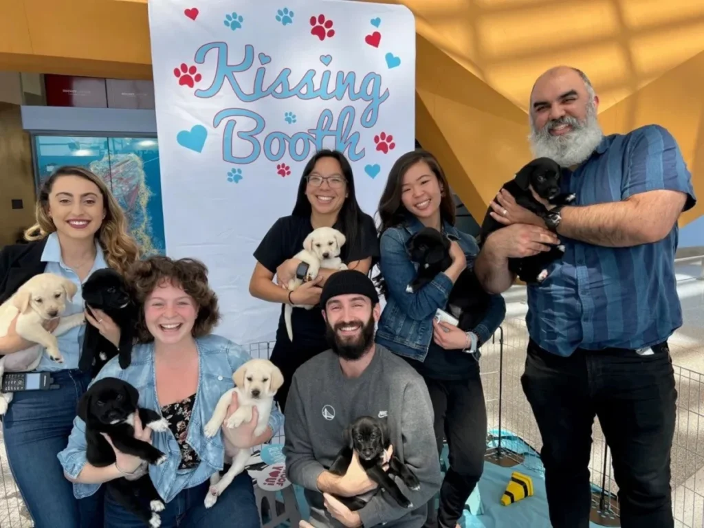 Puppy kissing booth corporate event activity with employees holding puppies, creating an engaging and stress-relieving experience