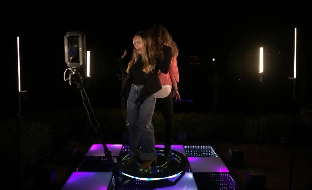 Two women dancing on an illuminated platform with professional lighting setup - perfect for corporate event photo booths