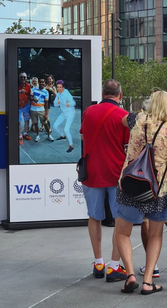 Visa-sponsored Tokyo 2020 Olympic digital display with visitors viewing branded photo opportunity in urban setting