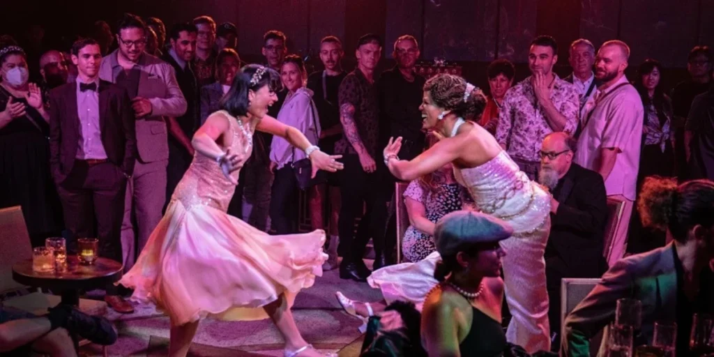 Wedding reception dance floor with two brides in white dresses celebrating surrounded by cheering guests