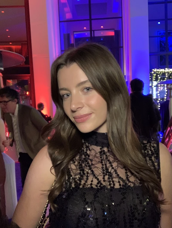 Woman in elegant black lace dress at an event with colorful lighting, representing sophisticated AI-enhanced event photography