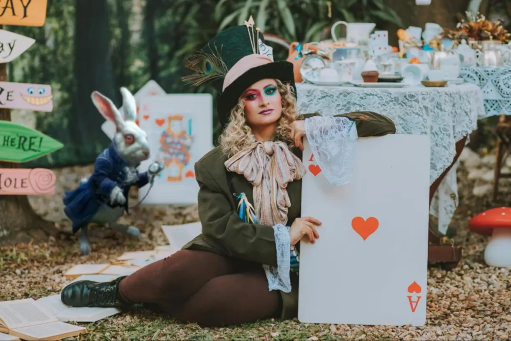 Alice in Wonderland themed event with Mad Hatter costume, playing card prop, and whimsical tea party setup