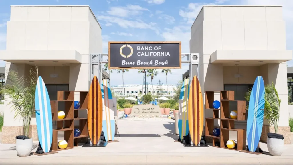Beach-themed corporate event entrance with surfboards and palm trees at Banc of California Beach Bash