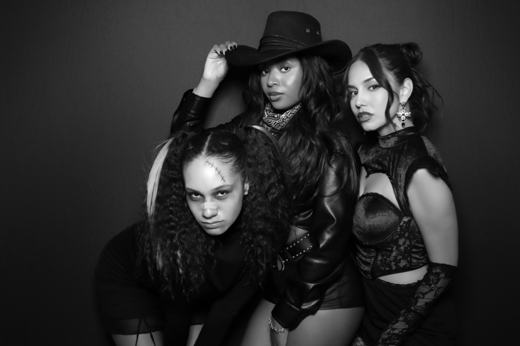 Black and white photoshoot of three women in western and gothic-inspired outfits - dramatic themed party photo opportunity