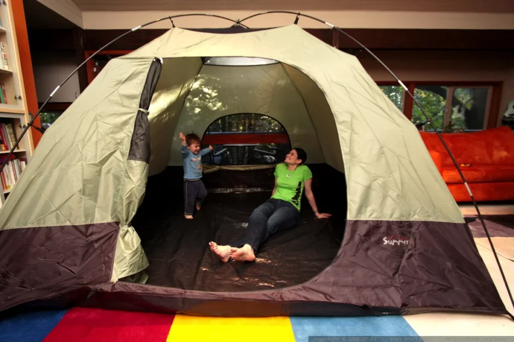 Indoor camping setup with tent in living room, inspiration for adventure-themed family events or children's parties