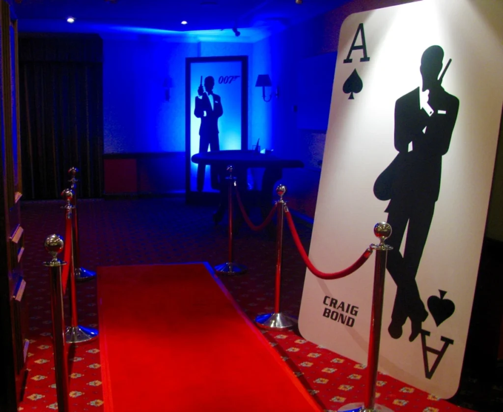 James Bond 007 themed event setup with red carpet entrance, playing card decoration, and silhouette backdrop with blue lighting