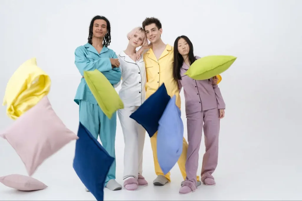 Models posing in colorful matching pajama sets with decorative pillows for a stylish slumber party themed photoshoot