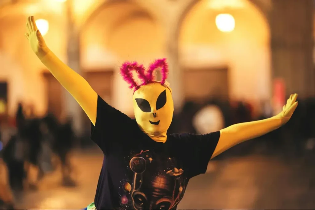 Person in yellow alien mask with pink bunny ears at a themed costume party - perfect for sci-fi or space-themed events