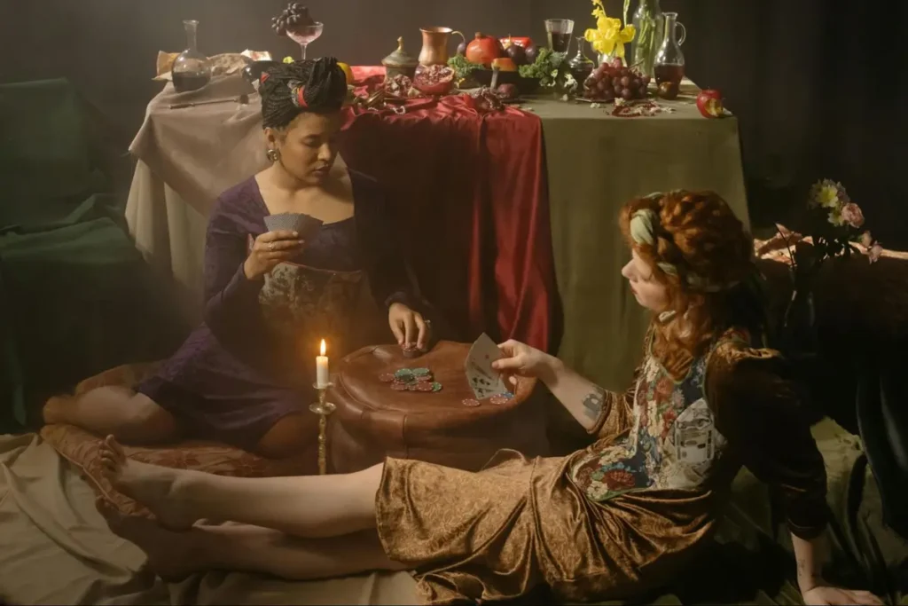 Renaissance-inspired card game event with women in period costumes playing cards by candlelight with feast table