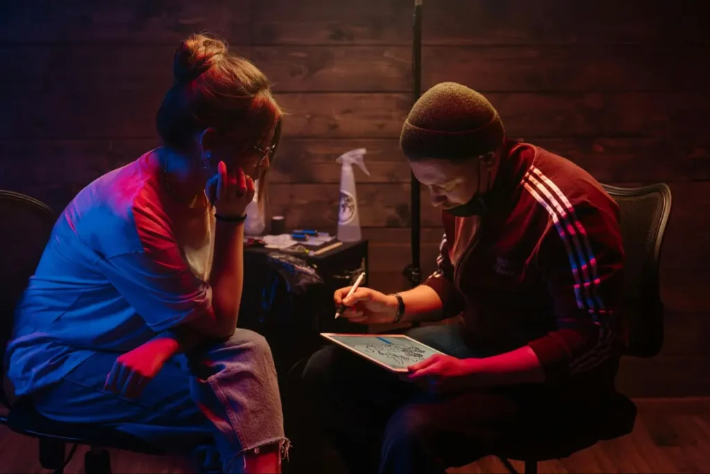 Tattoo artist working on a design in a moody red and blue lit studio space - creative workshop event setup