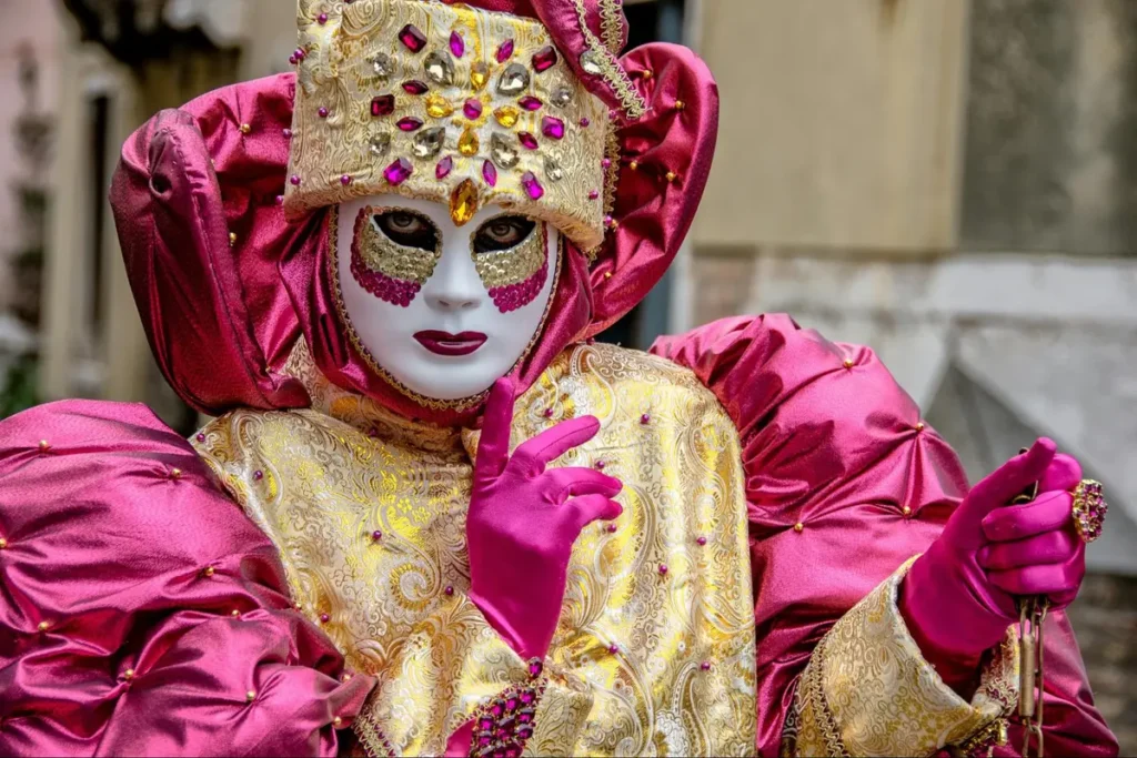 Venetian carnival theme costume with ornate pink and gold mask and elaborate traditional attire