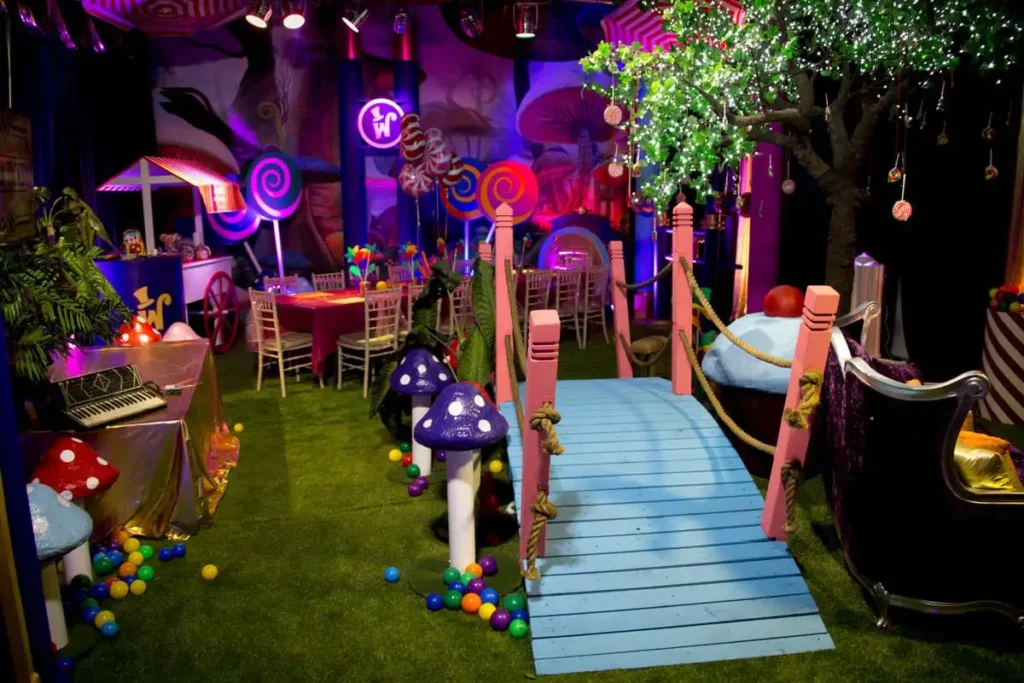 Whimsical Wonderland event venue with mushroom decorations, candy-themed props, blue walkway and illuminated tree