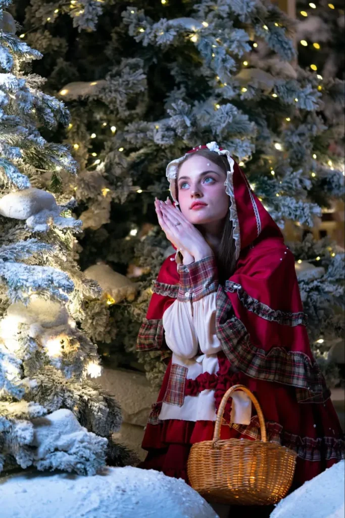 Woman in Little Red Riding Hood costume against snowy Christmas trees - fairy tale themed holiday event inspiration