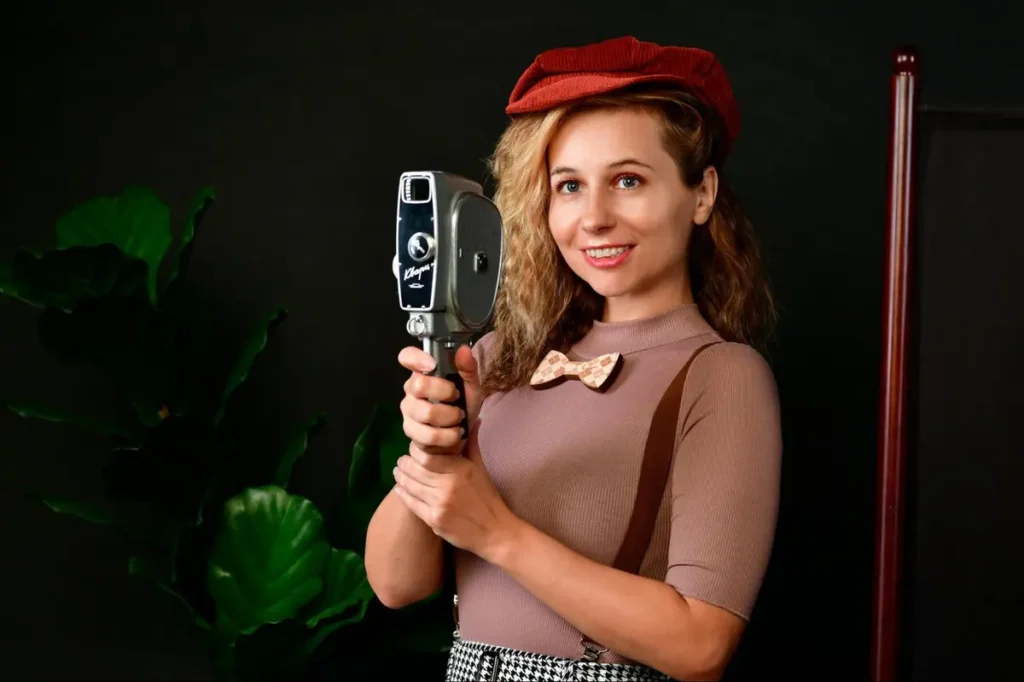 Woman in vintage attire holding retro film camera - Nostalgic cinema or vintage photography themed event with classic equipment