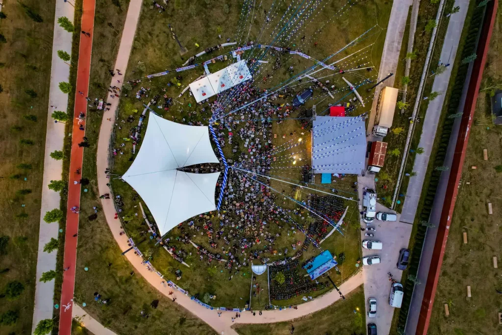 Aerial view of an outdoor event with a white stage canopy and crowd, capturing venue layout for brands