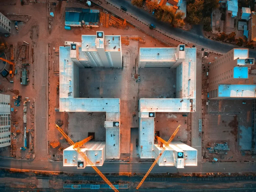 Overhead drone shot of a commercial construction site with cranes, capturing project progress for businesses