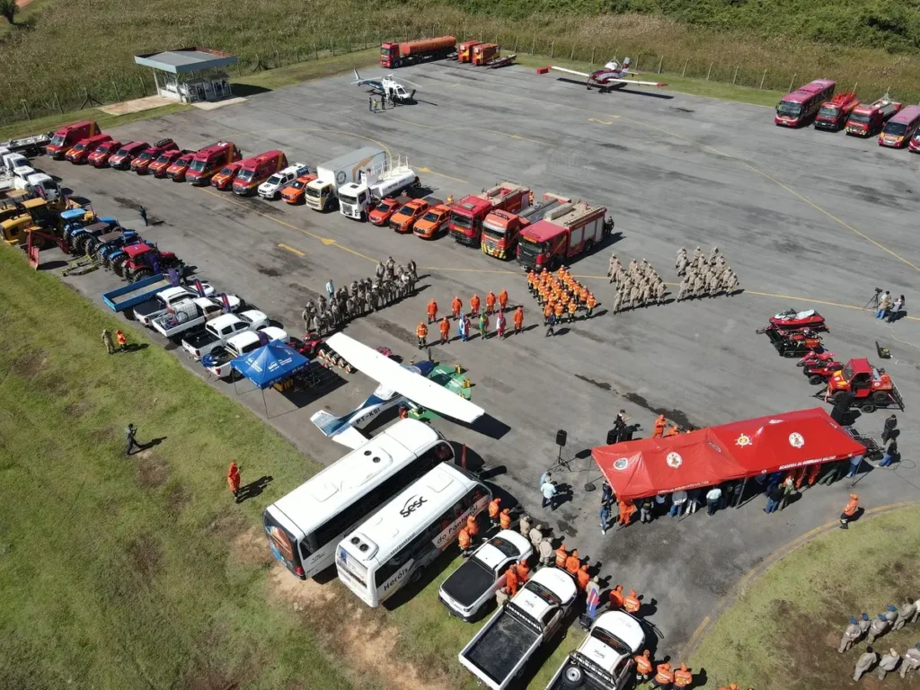 Drone aerial view of a large corporate event featuring commercial vehicles, equipment, and employees assembled in an outdoor operations yard for a company gathering and team event.