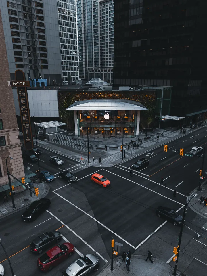 Drone aerial view of a premium retail storefront at a busy city intersection highlighting commercial architecture and surrounding business district